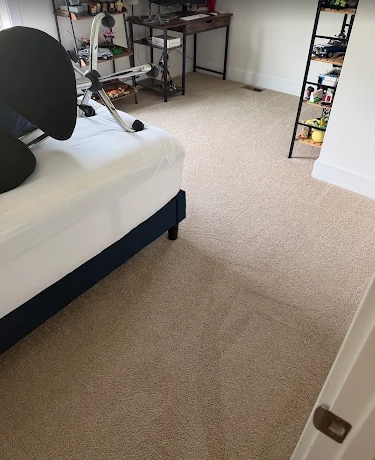 Same bedroom carpet before cleaning, with a visible stain and traffic lanes
